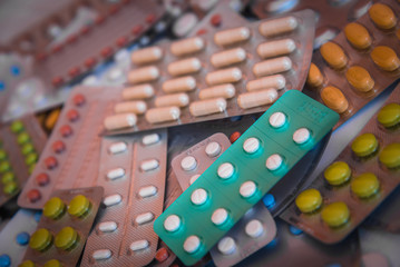 Heap of colorful tablets and capsules in blister package. Pharmaceutical industry concept. Pharmacy background. Selective focus