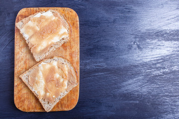 sandwiches with pollock roe on a wooden kitchen board against black background, top view