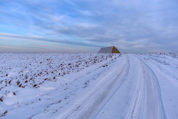 winter landscape with view of a stack of straw on the snowy field