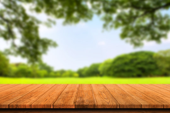Empty wooden table isolated on blurred green nature background. For your product placement or montage with focus to the table top in the foreground. Empty wooden brown shelf. shelves