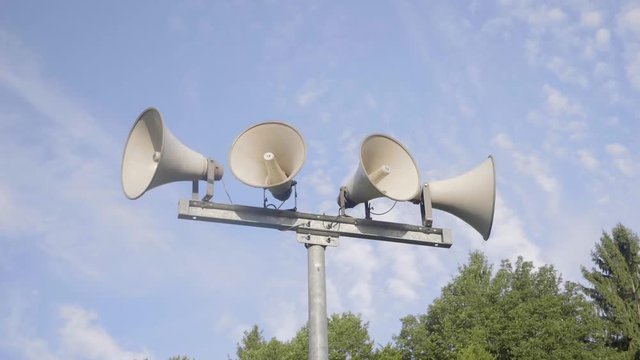Loudspeaker warning system. System of alert for population. Sound amplifier with loudspeaker against the sky and fresh green forest.