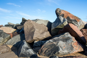 Pile of multicolored rocks and boulders as coastal erosion beach sea flood defence
