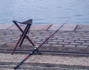 Empty folding chair of the fisherman and fishing rod