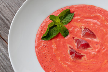Vegetarian dish. Gazpacho soup made from tomatoes, cucumbers, pepper, lemon juice and pine nuts, decorated with basil and ice.