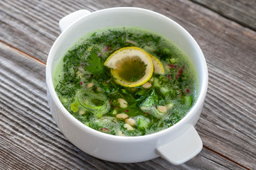 Raw food okroshka - a soup of cucumber, radish, avocado, leek, pine nuts and greens, decorated with a slice of lemon. Okroshka is a national dish of Russian cuisine.