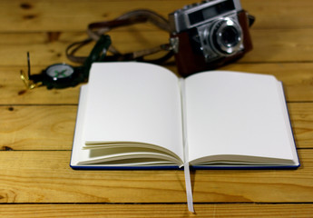 An empty travel journal with old-fashioned camera and compass