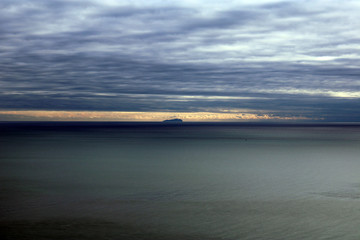 Mare al tramonto con isola all'orizzonte e cielo plumbeo