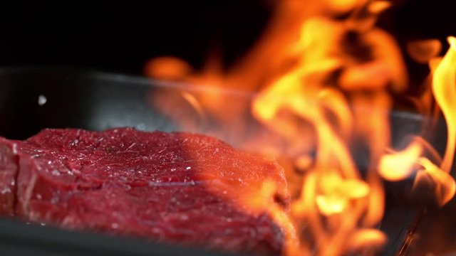 Super slowmotion footage of throwing fresh beef meat and seasoning on ignited pan, 1000fps 4k