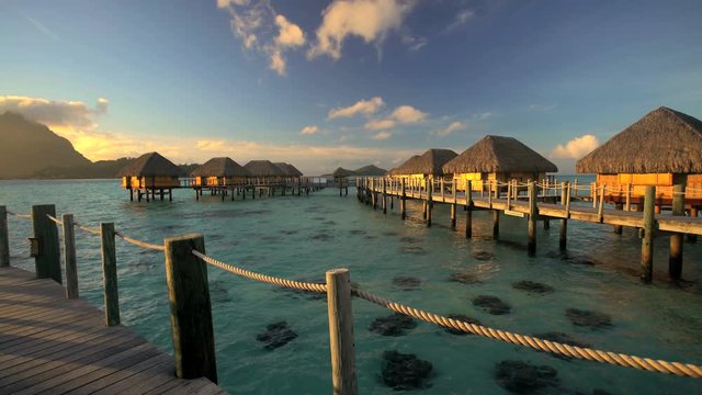 Walkway at sunrise to Overwater luxury Bungalows in tropical lagoon hotel resort of Bora Bora Island South Pacific French Polynesia