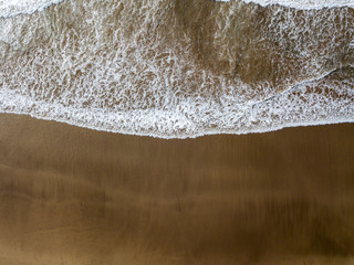 Vista aerea di una spiaggia, bagnasciuga, onde che si infrangono sulla costa. Spiaggia di Famara, Lanzarote, isole Canarie, Spagna