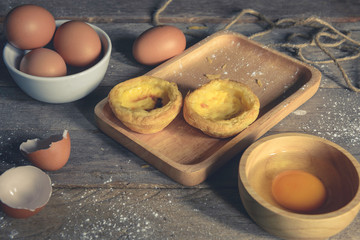 Egg tart on a wooden plate, the background is out of focus.