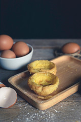 Egg tart on a wooden plate, the background is out of focus.