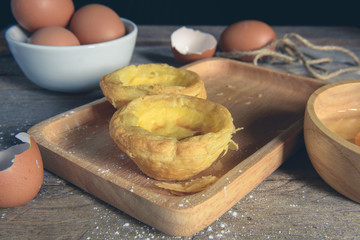Egg tart on a wooden plate, the background is out of focus.
