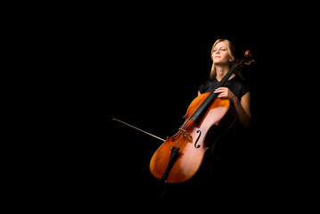 Young girl playing the cello on isolated black background - obrazy, fototapety, plakaty