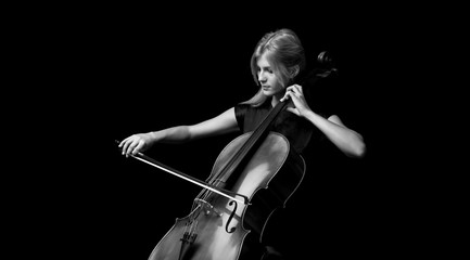 Young girl playing the cello on isolated black background © luismolinero