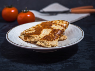 Light breakfast of omelet and tomato, close-up, dark background