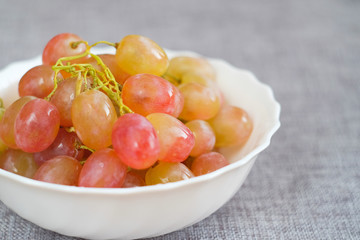 Grapes in a porcelain plate. Ripe pink Muscat grapes.