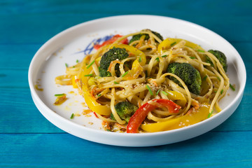 Asia food. Stir fry udon noodles with vegetables on a blue wooden backgound, cooked in wok