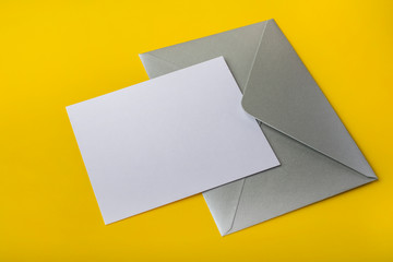 Mock-up letter or card with a silver envelope on a yellow background. Copy space