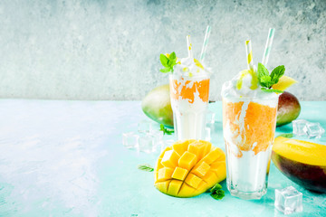 Tropical sweet dessert drink. mango milkshake or smoothie cocktail, with mango slices, mint and ice...
