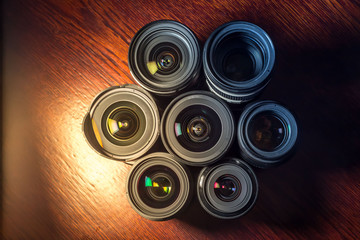 Set of various DSLR lenses with colorful reflections on wooden table
