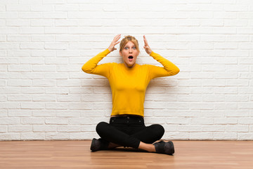 Young girl sitting on the floor with surprise and shocked facial expression