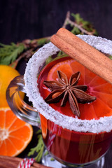 Hot mulled wine with slices of citrus fruits, cinnamon and anise in an Irish glass decorated with sugar border. Close-up