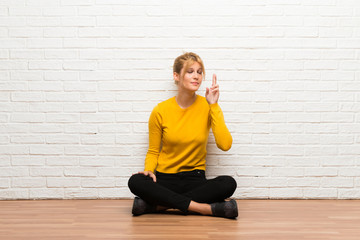 Young girl sitting on the floor with fingers crossing and wishing the best