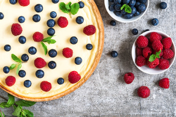 Classic New York cheesecake with fresh berries and mint on stone background, top view