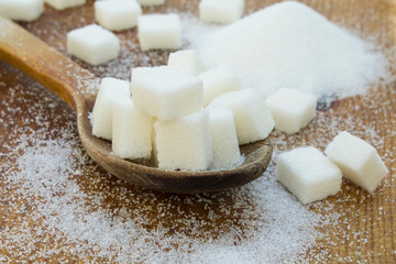 White sugar in wood spoon on wooden table.