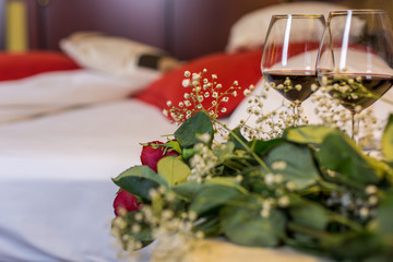 Two wine glasses and roses in a hotel bedroom