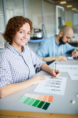Young smiling designer working over new fashion project or order in workshop