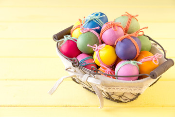 Fototapeta na wymiar Basket with Easter eggs on a yellow table