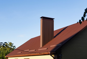 Roof with a chimney made of brown profiled sheeting, close up