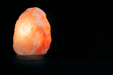 Salt lamp isolated against a black background. Mindfulness concept and esoterism. Empty copy space for Editor's text.