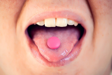 Open mouth holding medicine pill on tongue. Woman taking medicine. Healthcare and medicine concept