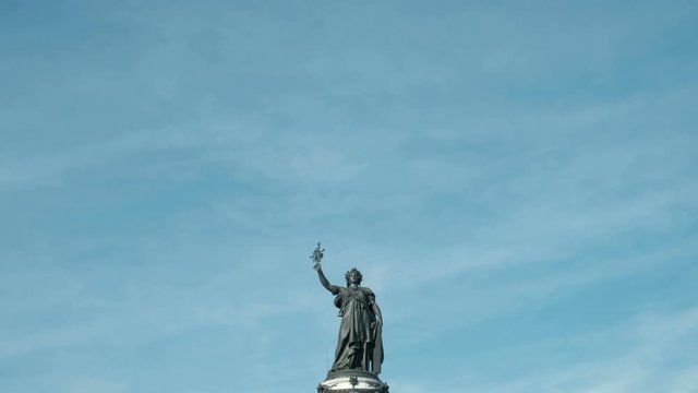 Camera tilt down from sky to reveal Marianne statue at Place de la Republique in Paris, France