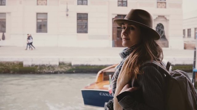 Cinematic shot of happy young beautiful tourist woman enjoying atmospheric boat trip along city river in Venice Italy.