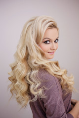 Charming smiling blonde with luxurious blonde curls. Hair beauty