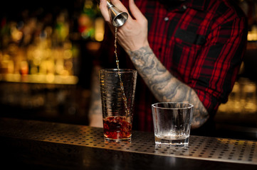 Barman pouring strong alcohol into a cocktail glass