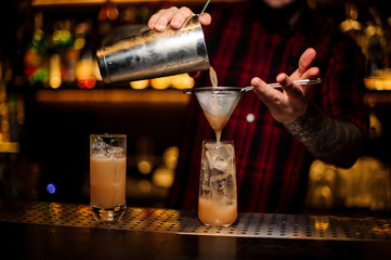 Barman pouring fresh lemonade cocktail into a glass