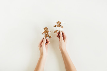 Gingerbread man and woman cookies in female hands isolated on white background. Flat lay, top view Christmas / New Year composition.