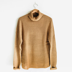 Feminine jumper on hanger at white wall. Woman fashion clothes concept.