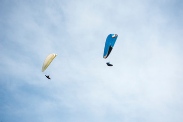 Two paragliders flying in the blue sky against the background of clouds. Paragliding in the sky on a sunny day.