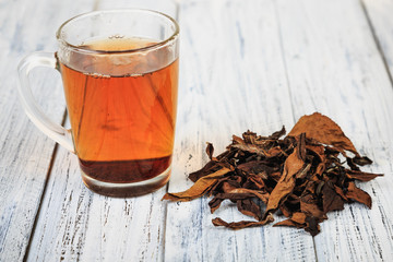 Cup of black tea and tea leaves