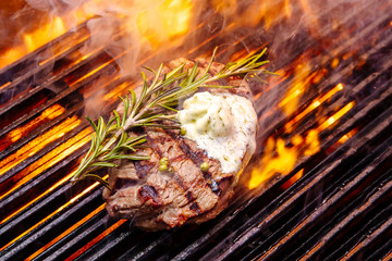 steak on a grill fire, with herbs and butter