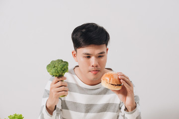Man having hard choice between healthy and unhealthy food