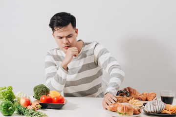 Man having hard choice between healthy and unhealthy food