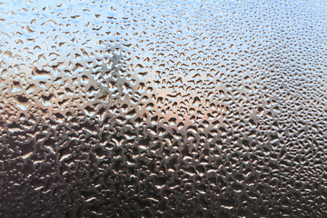 The frozen drops on the patterned frosty winter window