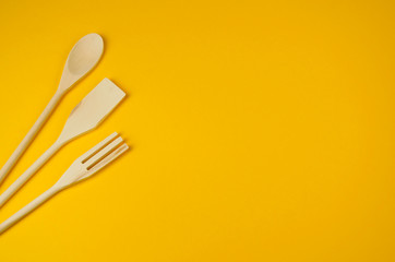Natural wooden cooking kit on yellow background. Organic food concept.